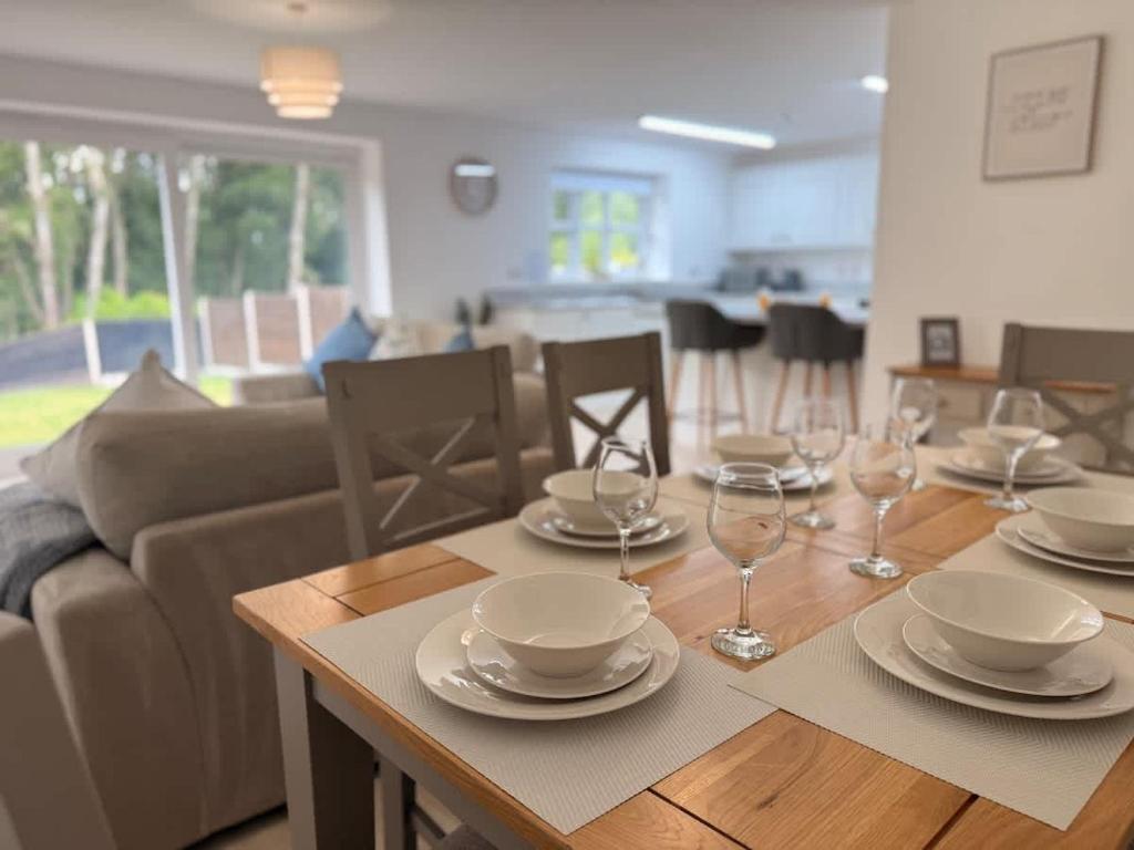 a dining room table with plates and wine glasses on it at Low Street Escape 3 Bed, Sleeps 9, Gated Drive, WiFi, Contractors in Great Wyrley