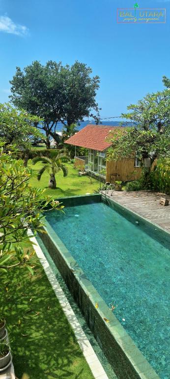 a swimming pool in front of a house at Rumah Putih Beachfront Bungalow in Tegallengah