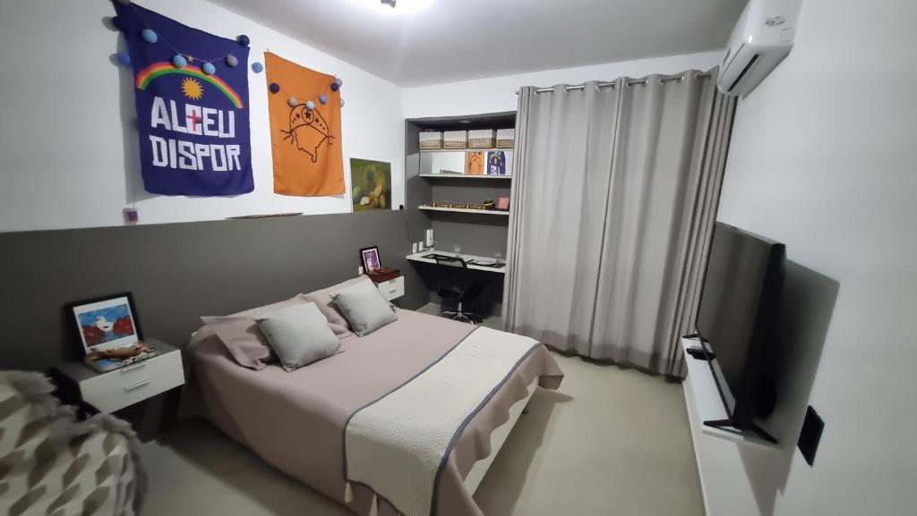 a bedroom with a bed and a television and a desk at Quarto Vista Mar in Recife