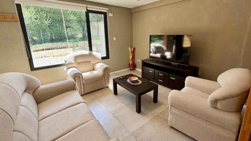 a living room with two couches and a flat screen tv at Cabañas Indómita in El Bolsón
