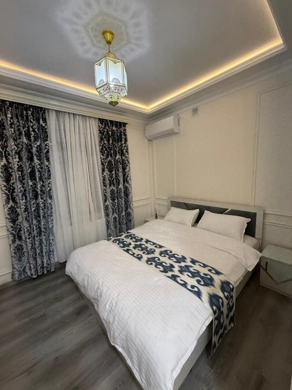 a bedroom with a large white bed with a chandelier at Ayvon Guesthouse in Samarkand