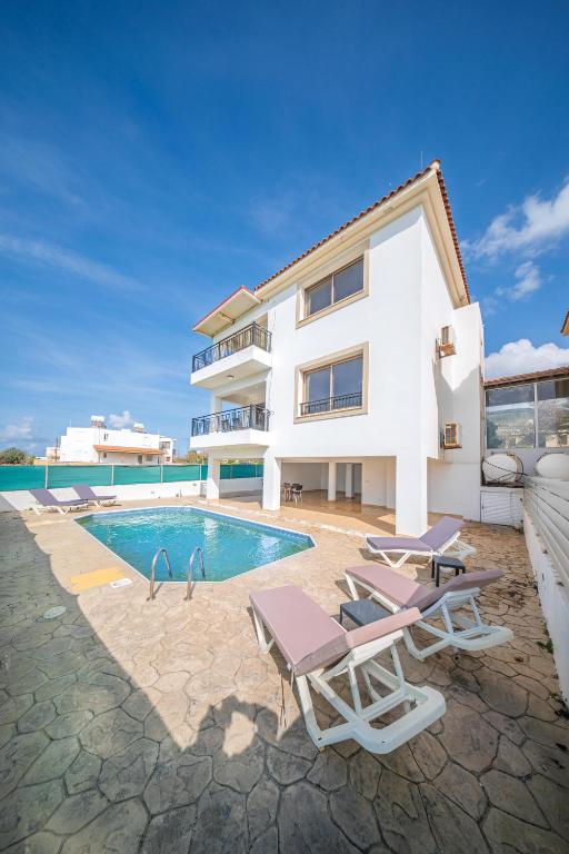 a house with a swimming pool next to a building at Infinity Blue Villa w Pool in Pomos