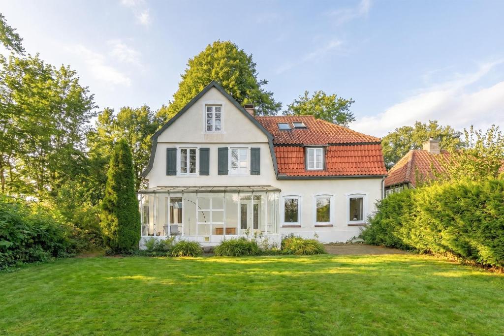 an exterior view of a white house with a yard at Historisches Landhaus mit Outdoor-Sauna in Ostenfeld
