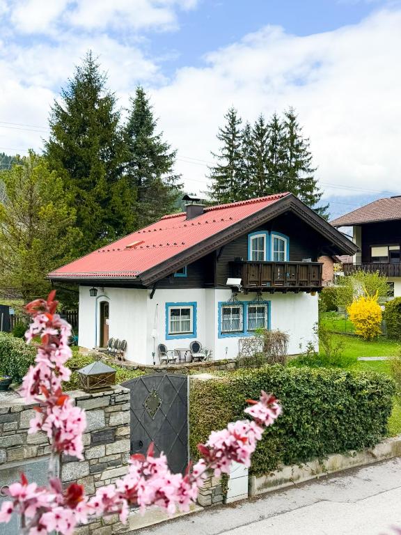 a white house with a red roof and pink flowers at Rosis Cottage in Lienz
