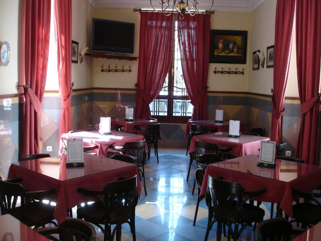 a dining room with tables and chairs and red drapes at Hotel Villa Maria in Cabra
