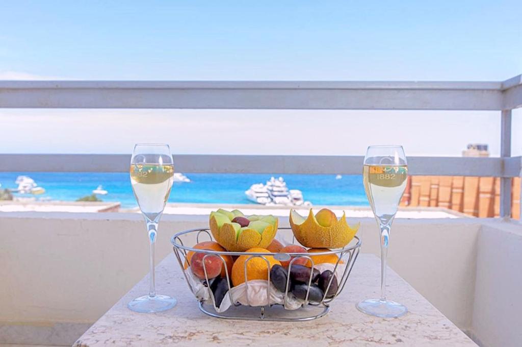 two glasses of wine and a bowl of fruit on a table at Dexon Roma Down Town Hotel in Hurghada