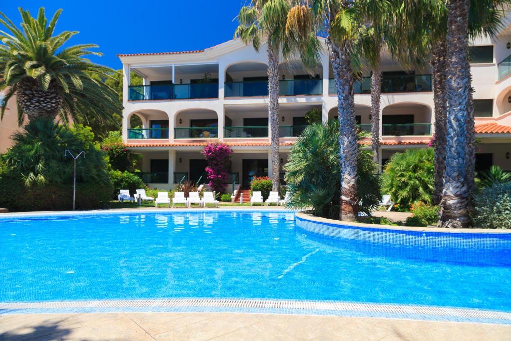una piscina frente a un hotel con palmeras en UHC Costa Linda Family Complex, en Hospitalet de l'Infant