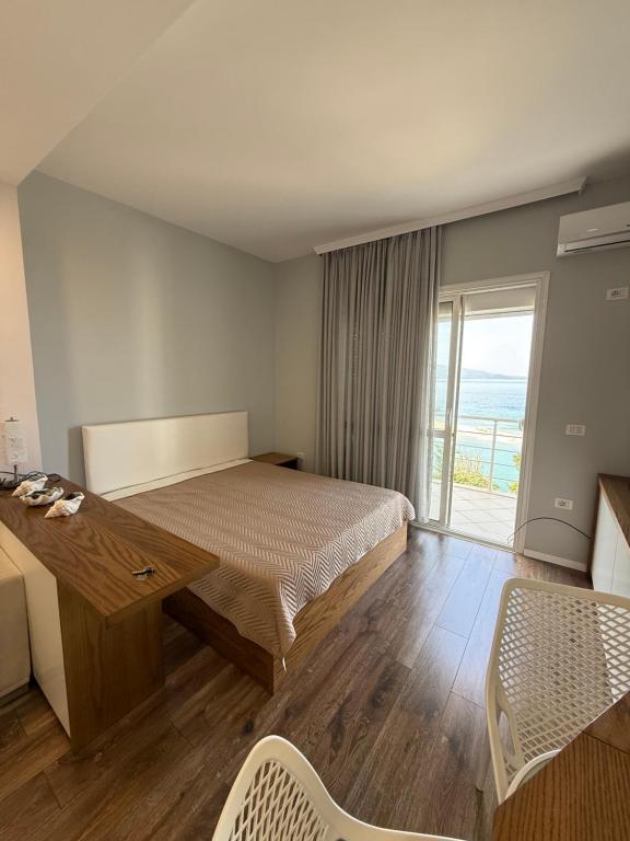 a bedroom with a bed and a desk and a window at Beachfront Apartment Saranda in Sarandë