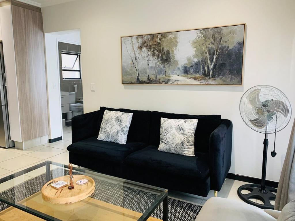 a living room with a black couch and a glass table at The Bridge at Montego in Fourways