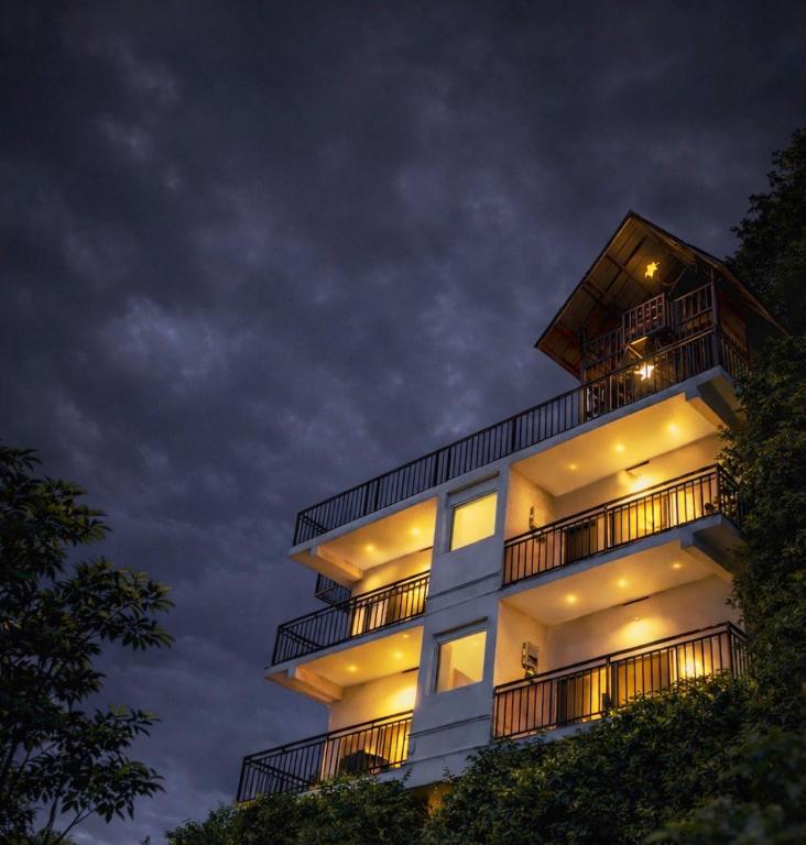 a tall white building with balconies at night at Skyscenic Munnar in Munnar
