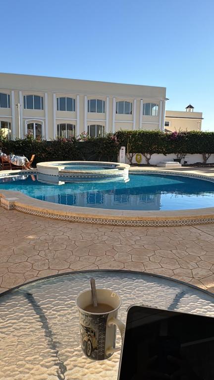 a cup of coffee sitting on a table in front of a swimming pool at Villa Nita Altaona Golf Turquoise Sleeps 4 adults in Baños y Mendigo