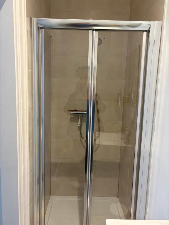 a glass shower stall with a person in the background at Binghambelle in Bangor