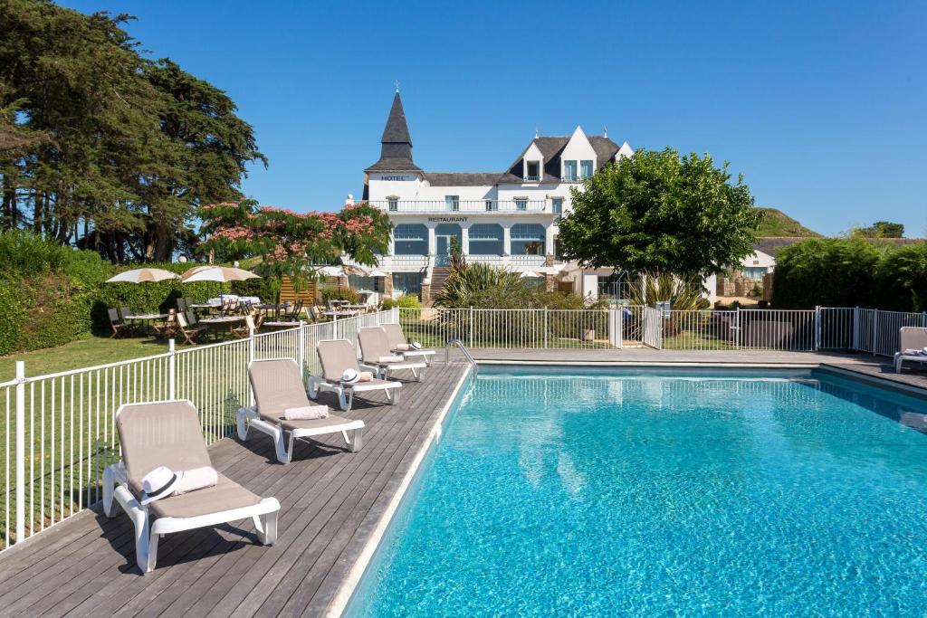 a swimming pool with chairs and a house in the background at Hotel Restaurant Spa du Tumulus Carnac in Carnac