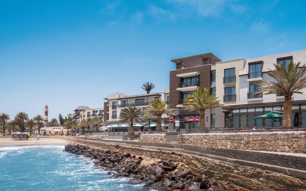 uma vista para uma praia com edifícios e palmeiras em Strand Hotel Swakopmund em Swakopmund