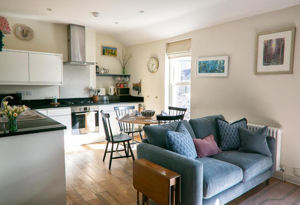 a living room with a blue couch and a kitchen at The Green House deluxe 2 bedroom upper floor apartments in Harrogate