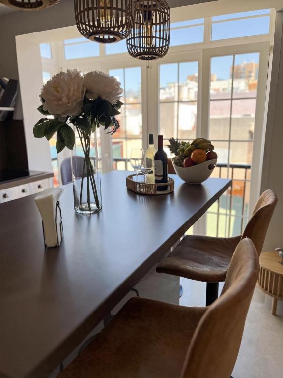 a table with a vase of flowers and a bowl of fruit at Casa Carmela Fuengirola in Fuengirola