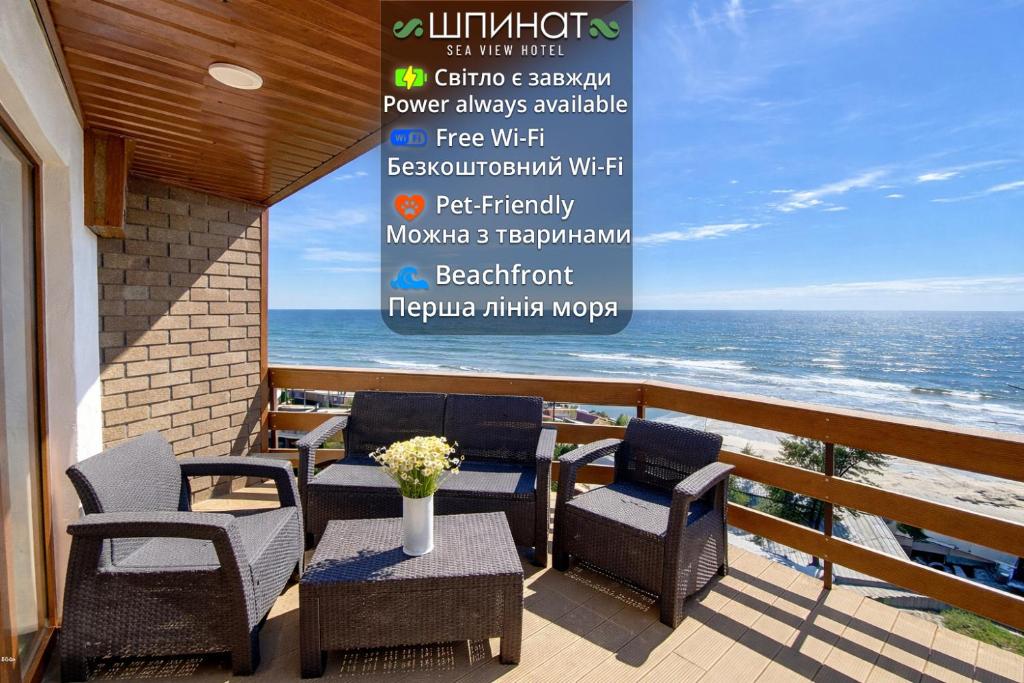 a balcony with chairs and tables and a sign with the ocean at Shpinat in Odesa