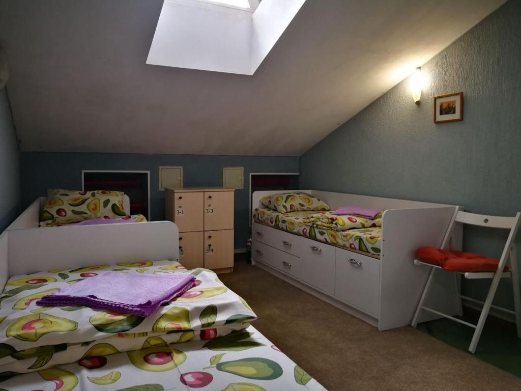 ein Dachgeschoss-Schlafzimmer mit zwei Betten und einem Stuhl in der Unterkunft хостел Мансарда in Kiew