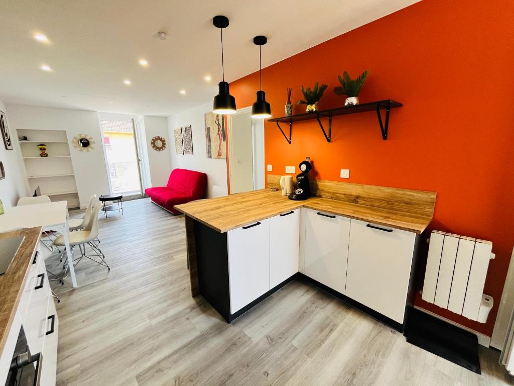 an orange kitchen with white cabinets and a red wall at Le Vinois Climatisation 2 chambres balcon in Vinay