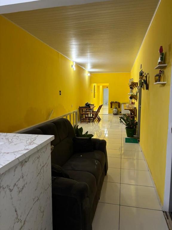 a living room with a couch and a yellow wall at pousada palmeiras bhs in Barreirinhas