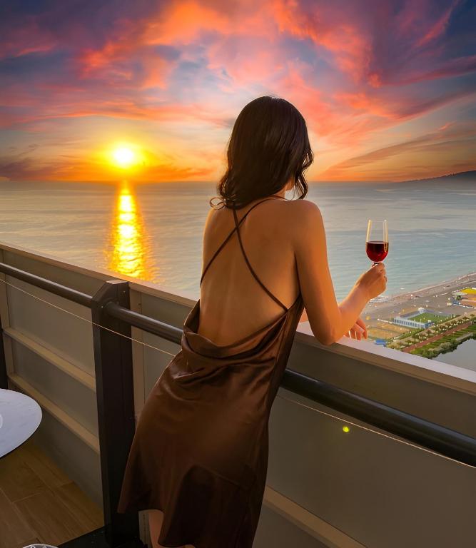 a woman in a dress holding a glass of wine at Sea View Witch Panoramic Aparthotel in Batumi