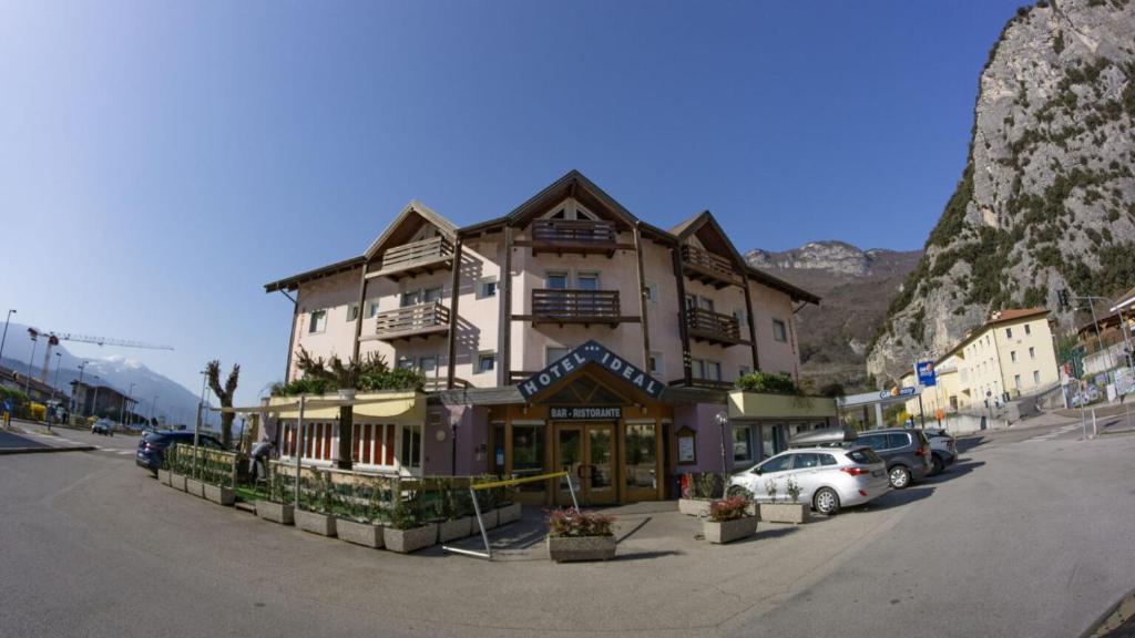 ein großes Gebäude, vor dem Autos parken in der Unterkunft Hotel Ideal in Sarche di Calavino