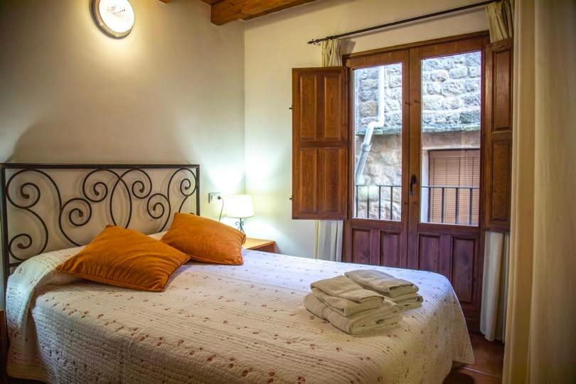 a bedroom with a bed with orange pillows and a window at Casa Tomás in Calaceite