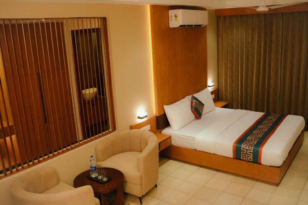 a hotel room with a bed and a chair at Hotel Bariz Perinthalmanna in Perintalmanna