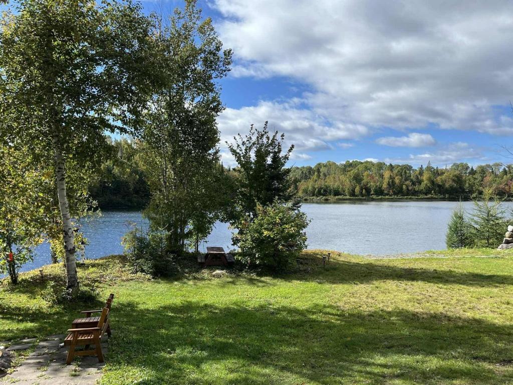 a park bench sitting in the grass near a lake at Havre du Lac Montagnais in Saint-Fulgence
