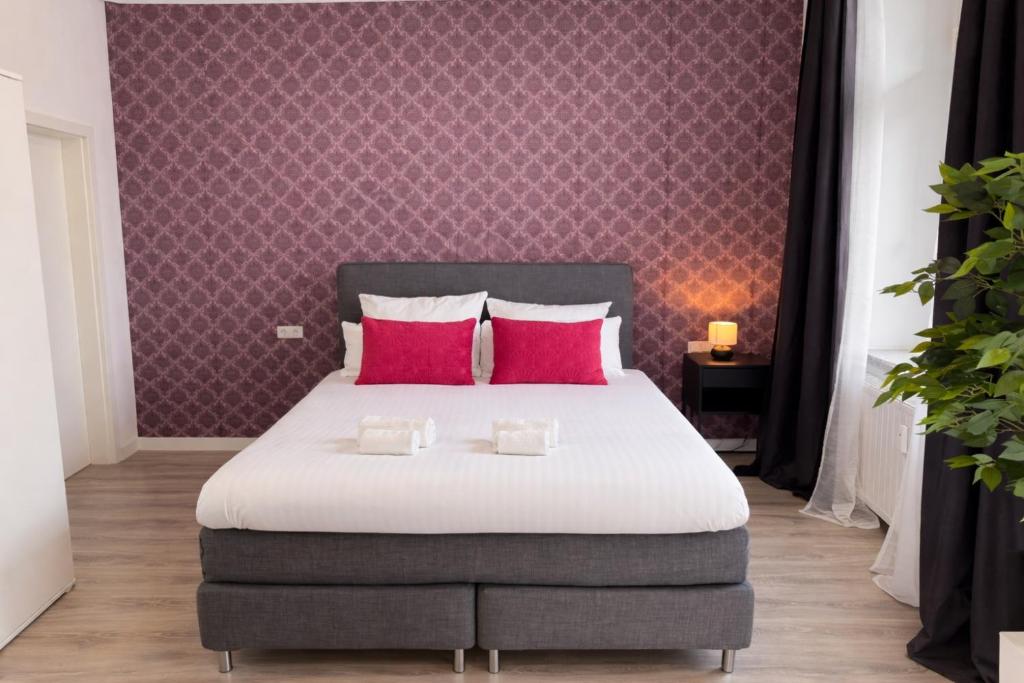 a bedroom with a large bed with red pillows at MIILOX Apartments Chemnitz Hainstrasse in Chemnitz