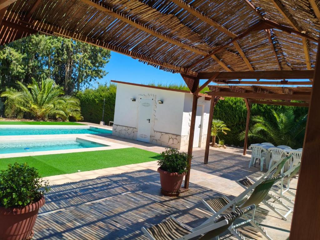 a patio with chairs and a swimming pool with a straw roof at Casa Rural "La villa del pistacho" in Archivel