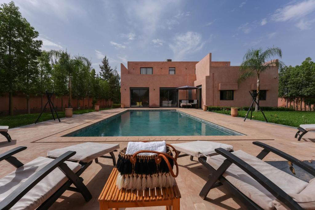 a swimming pool with two chairs and a house at Dar El Gharrabia villa entièrement privatisée in Amezrou