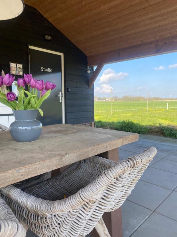 a wooden picnic table with a vase of flowers on it at Studio op Camperplaats Vechtdal in Nieuwleusen