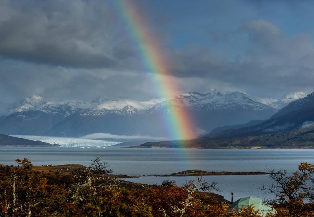 a rainbow over a body of water with mountains at Moreno Camp - Glamping with a view in El Calafate
