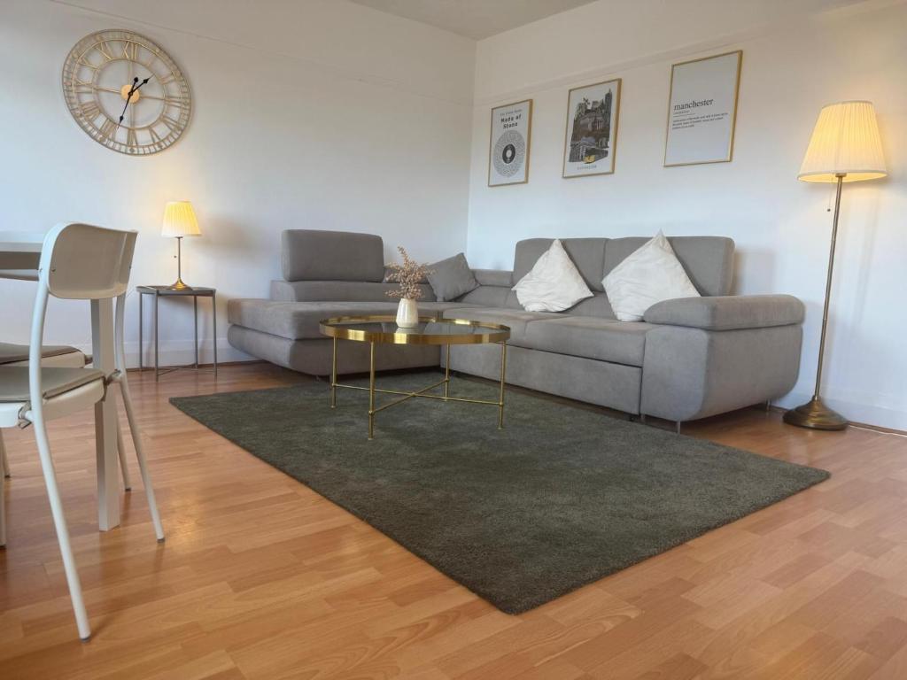 a living room with a couch and a table and a clock at The Cotton Mill Hideaway - One Bedroom Apartment - Free Parking near Etihad Stadium & CoOp Live in Manchester