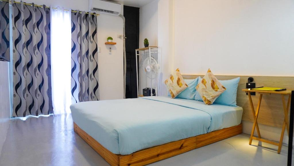 a bedroom with a bed with blue sheets and a window at Happy Island Inn in Virac