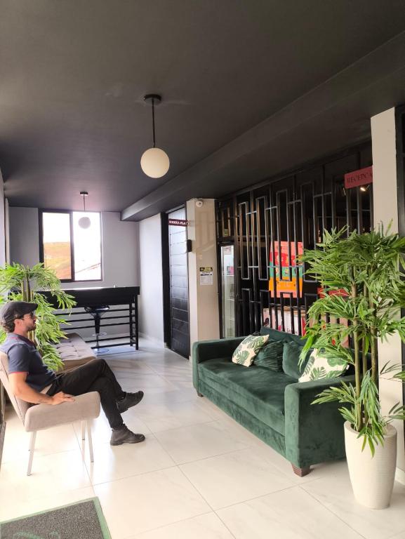 a man sitting on a couch in a living room at Zuppolini Garden apart-hotel in Bananeiras