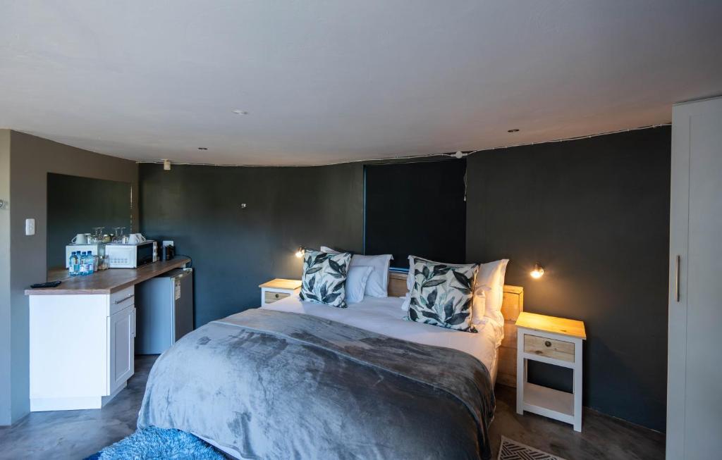 a bedroom with a large bed and a kitchen at A Stone's Throw in Grahamstown