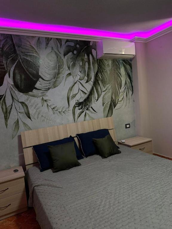 a bedroom with a large bed with a painting on the wall at apartament gezuar in Golem
