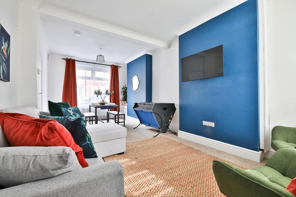 a living room with a blue wall and a tv at Cosy 3-Bedroom House Near Caerphilly Castle in Caerphilly