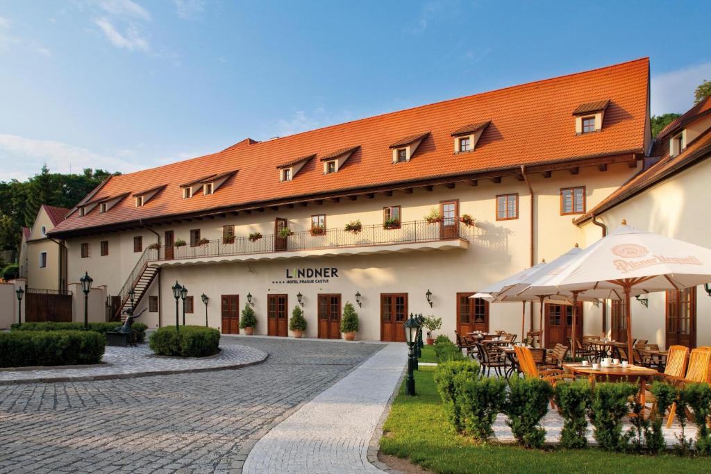a large building with an umbrella and tables and chairs at Lindner Hotel Prague Castle, part of JdV by Hyatt in Prague