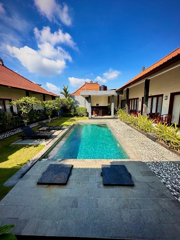 a swimming pool in front of a house at Plawa Bali Guest House in Canggu