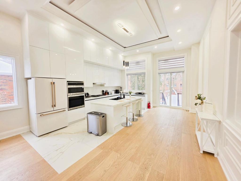 a large white kitchen with white appliances and wood floors at Luxury House with Open Living Space in Toronto