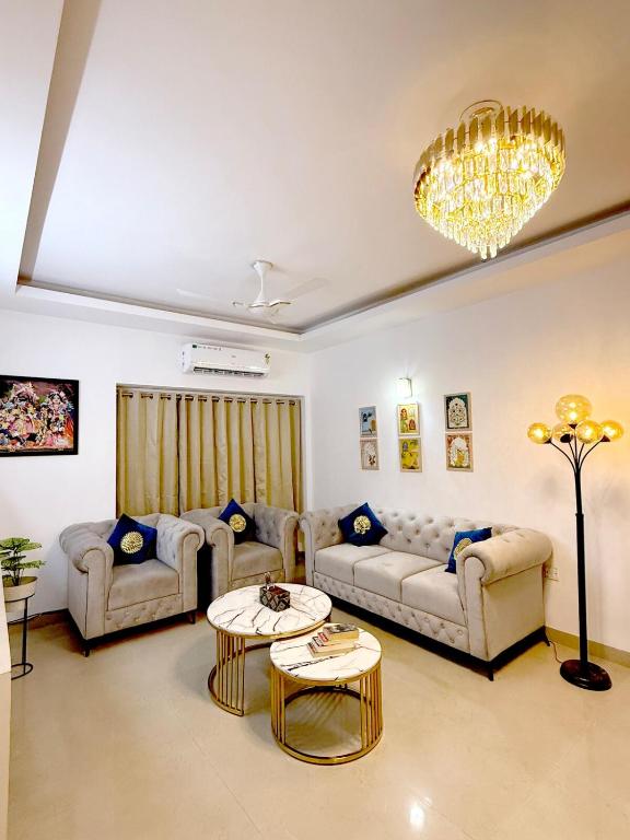 a living room with couches and a chandelier at Meera Kunj in Chhatikara