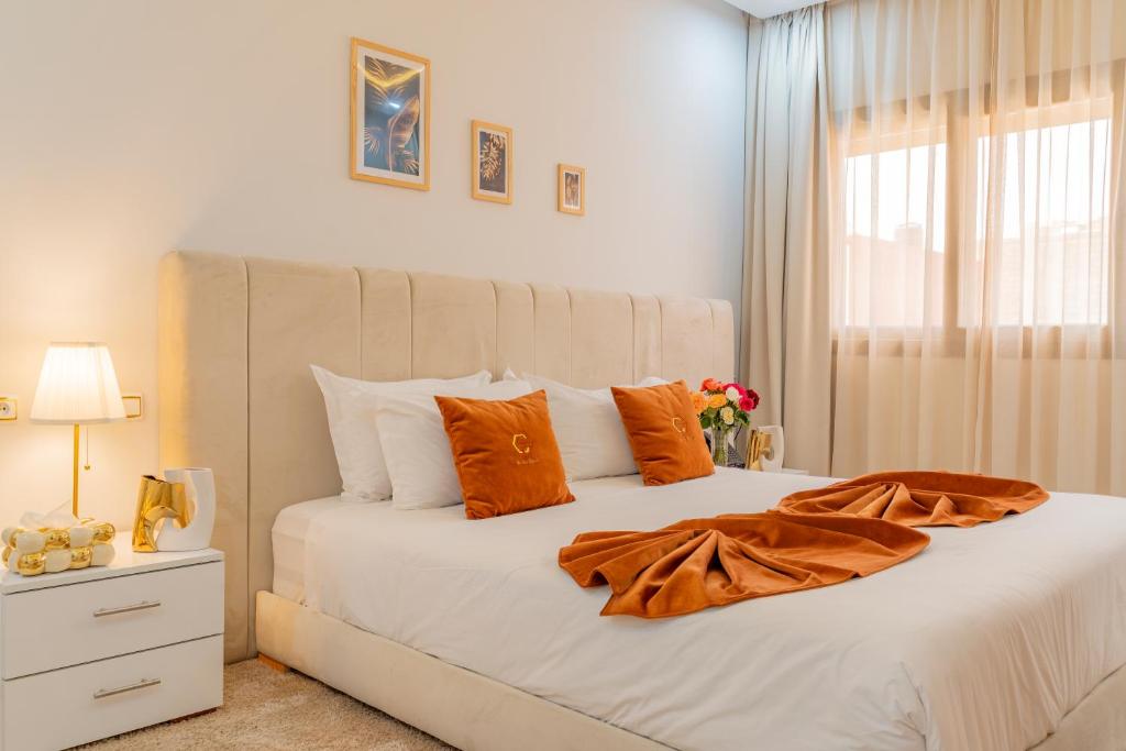a bedroom with a large white bed with orange pillows at Hotel Golden Sunset Dakhla in Dakhla