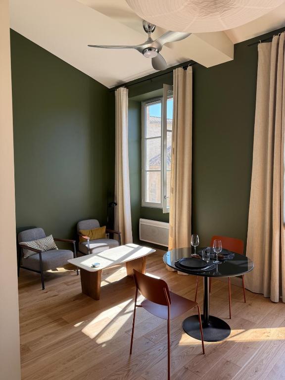 a living room with green walls and a table and chairs at Appartement calme et lumineux au cœur d'Arles in Arles