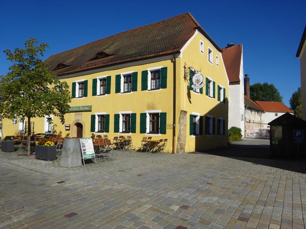 a large yellow building with green shutters on it at Schloß-Hotel Hirschau in Hirschau