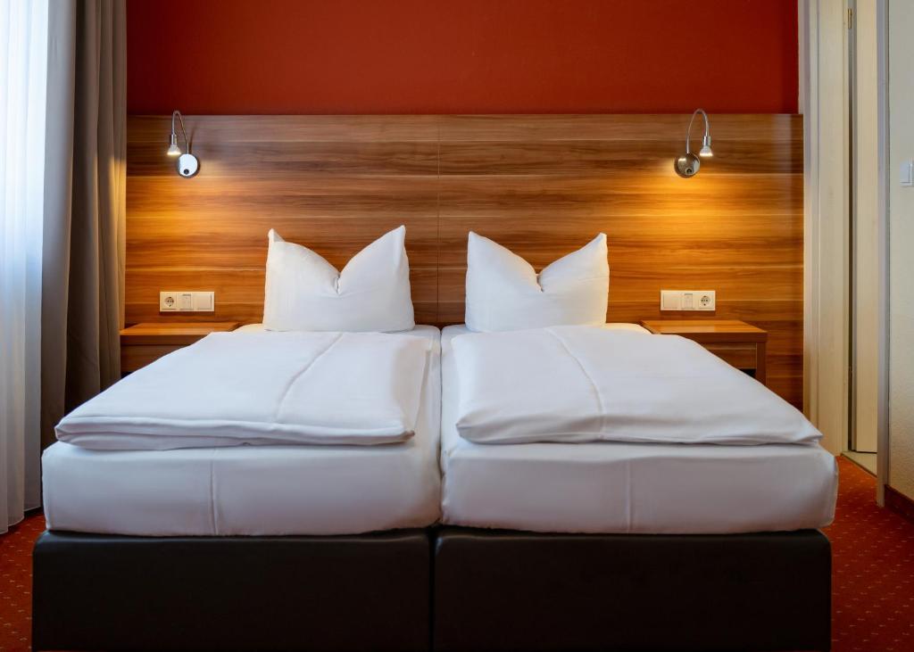 two beds with white pillows in a hotel room at Jägerheim in Nuremberg