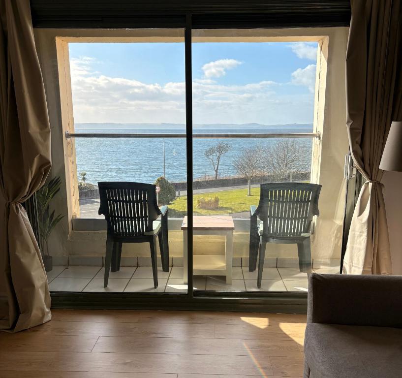 a room with two chairs and a view of the ocean at View of the Isles 2 in Largs