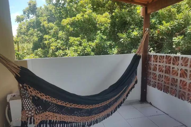 a hammock on a balcony with a view of trees at Kitnet com veranda in Conde